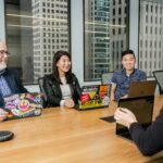 A diverse group of professionals engaged in a collaborative discussion around a table, symbolizing teamwork, resilience, and innovative leadership in the workplace.